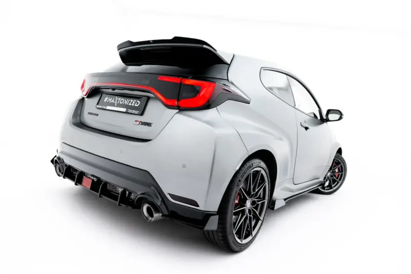 pol_po_Led-Stop-Light-Toyota-GR-Yaris-Mk4-Facelift-23789_5webp - OPSHOLDERS Rear three-quarter view of a gray sports car with a large black spoiler, red LED taillights, and exposed exhausts.