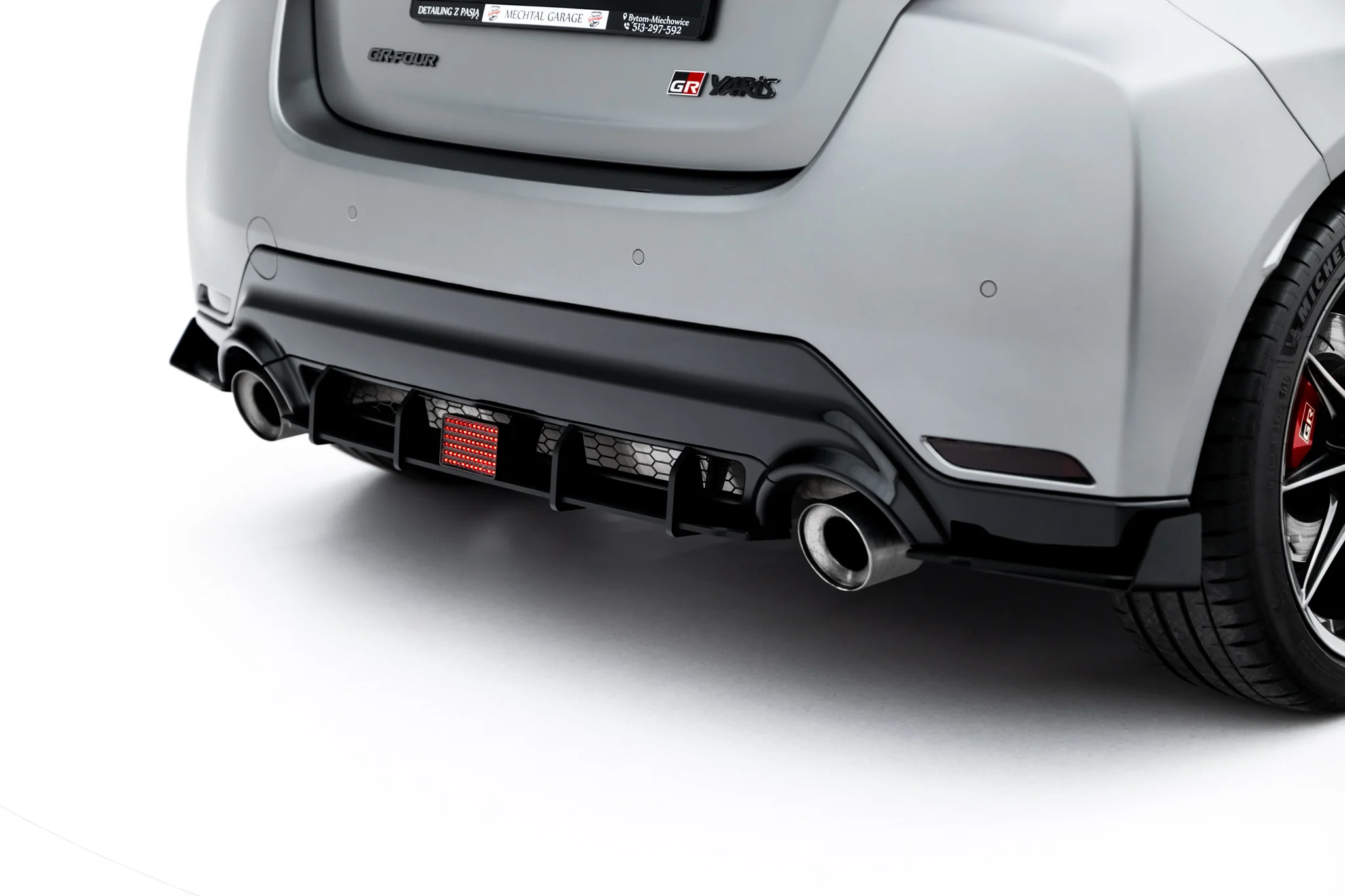 pol_po_Led-Stop-Light-Toyota-GR-Yaris-Mk4-Facelift-23789_6webp - OPSHOLDERS Rear view of a gray GR Yaris with diffuser, dual exhausts, and visible badge on the tailgate.