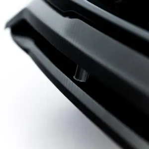 Close-up of a black carbon-fiber textured surface with glossy curved strips arranged diagonally.