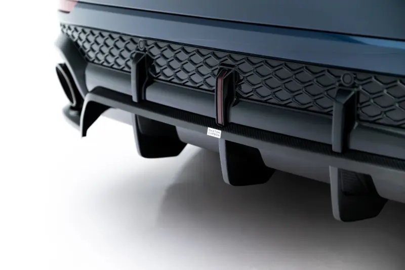 Close-up of a car front bumper with a honeycomb grille and a small Maxton Carbon badge