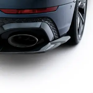 Close-up of a dark-blue car rear showing the exhaust, diffuser, and taillight details near the wheel.