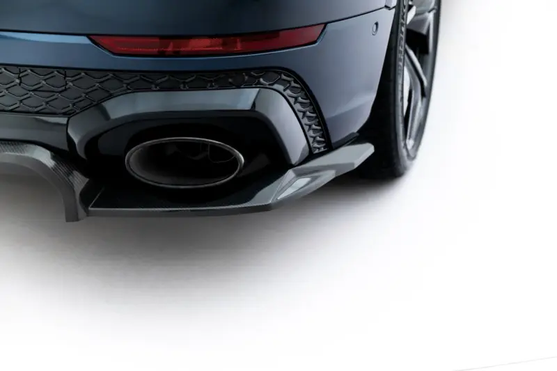 Close-up of a dark-blue car rear showing the exhaust, diffuser, and taillight details near the wheel.