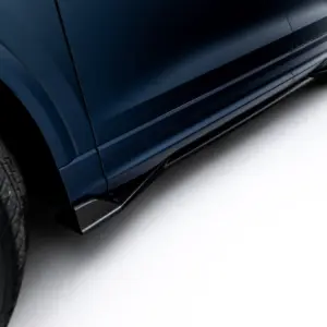 Close-up of a dark blue car's lower side panel and wheel, photographed from a low angle against a light background.