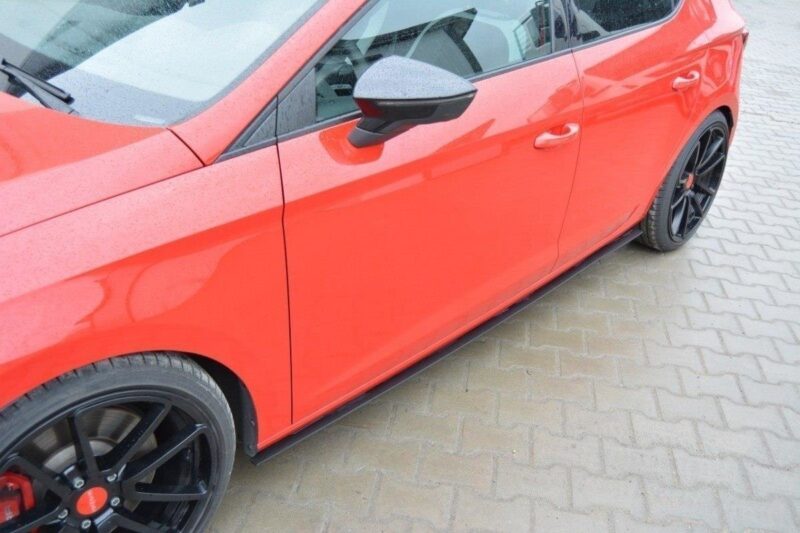 Red car side view showing front and rear doors, black alloy wheels, and a wet pavement surface nearby.