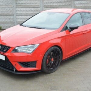 Red sporty hatchback with black multi-spoke wheels and front splitter parked on a paved driveway by a gray fence.