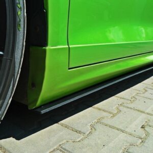 Close-up of a bright green car's lower side panel and wheel, showing a low ground-hugging side skirt on a paved parking area