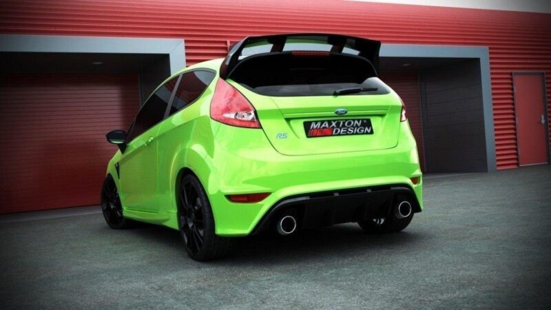 Lime‑green hatchback with a large rear spoiler and quad exhausts in a paved lot, Maxton Design badge on the rear.
