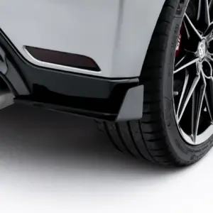 Close-up of a car's rear wheel, alloy rim and exhaust visible beneath the rear bumper.