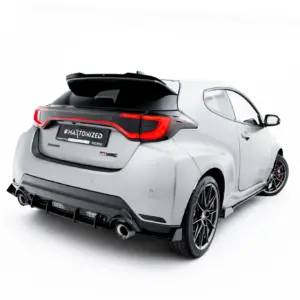 White sporty hatchback shown from rear-left angle with a black roof spoiler, red taillights, and large alloy wheels, highlighting an aftermarket rear kit.