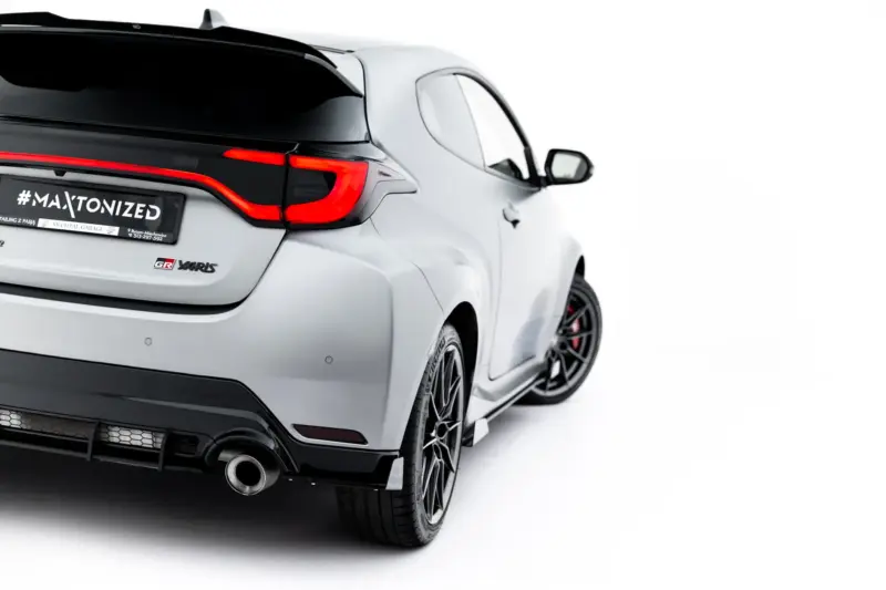 Rear-left of a silver Toyota GR Yaris with red L-shaped taillight, visible exhaust, and a '#MAXTONIZED' plate on a white background.