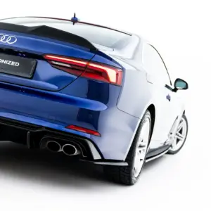 Rear three-quarter view of a blue Audi, showing taillights, quad exhausts, and a black license plate reading #MAXTONIZED.