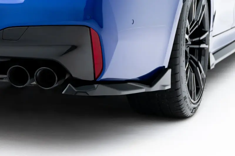Close-up of a blue car's rear corner with dual exhausts and a red tail light.