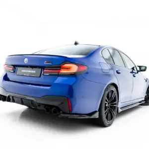 Blue BMW sedan shown from a rear three-quarter angle, featuring M Competition badge and a sporty rear diffuser.