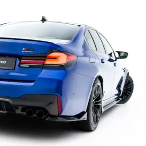 Blue BMW M5 Competition rear three-quarter view with illuminated taillights and quad exhausts, plate reading #MAXTONIZED on a white background
