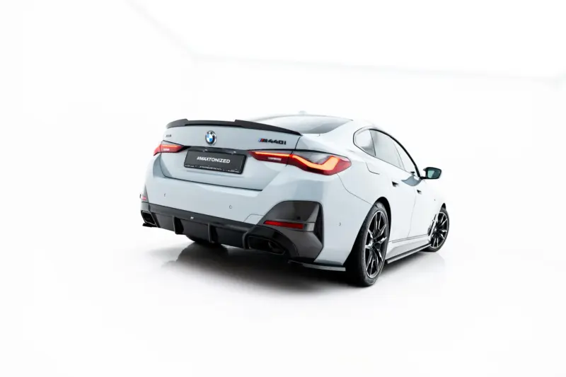 White BMW M440i viewed from the rear-left, featuring a carbon rear diffuser and red LED taillights on a white studio background.