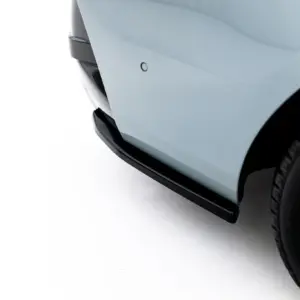 Close-up of a car's front fender and wheel, showing a circular parking sensor on light blue paint.