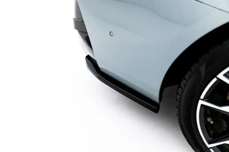 Close-up of a car's front fender and wheel, showing a circular parking sensor on light blue paint.