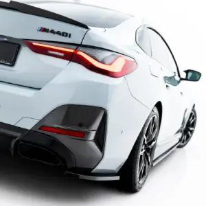 Rear three-quarter view of a white BMW M4, showing the taillight, badges, and carbon fiber rear bumper details.