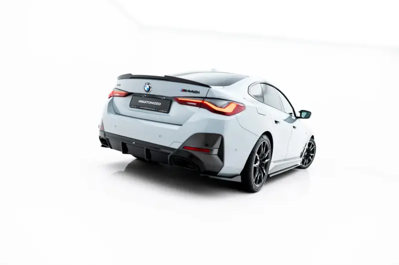 Rear three-quarter view of a white BMW M4 with red taillights and carbon rear diffuser, #MAKTONIZED plate visible