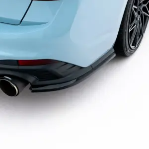 Close-up of a light-blue sports car's rear bumper, exhaust, and black alloy wheel visible on the right side.