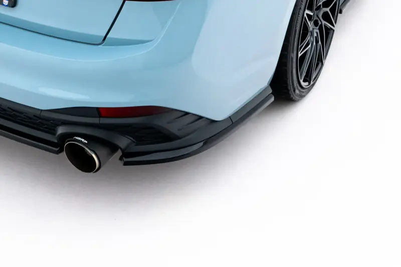 pol_po_Rear-Side-Splitters-Volkswagen-Jetta-GLI-Mk7-Facelift-2-23932_5webp - OPSHOLDERS Close-up of a light-blue sports car's rear bumper, exhaust, and black alloy wheel visible on the right side.