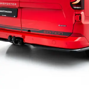 Rear view of a red vehicle showing a black license plate area with '#MAXTONIZED' and 'Edition' badge, 4MOTION emblem, and tow hitch visible under the bumper