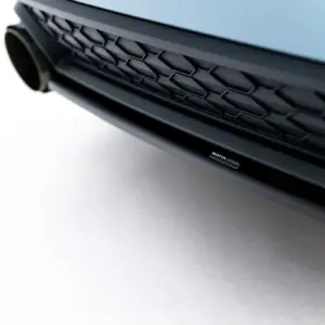 Close-up of a car front grille with a hexagonal pattern and a small Maxton Design badge visible on the lower edge of the bumper