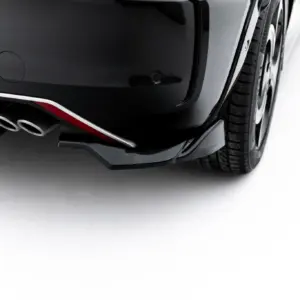 Close-up of a dark car's rear bumper with dual exhaust tips and part of the rear wheel visible.