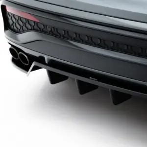 Close-up of a sleek car rear showing dual exhaust outlets, dark honeycomb rear grille, and a red taillight edge on the left edge of the image.