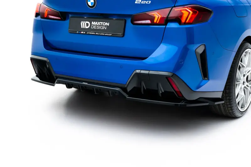 Blue car rear end with BMW badge, red taillights, and a Maxton Design license plate; showing the bumper and rear wheel area.