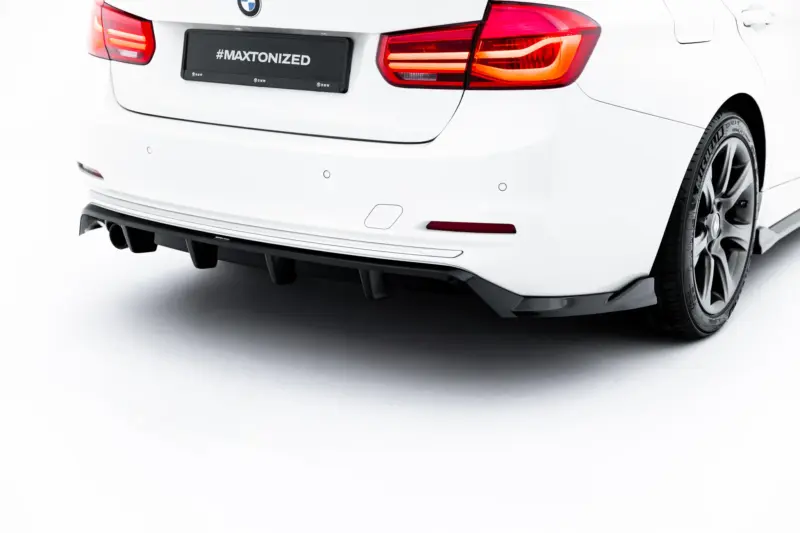 Rear view of a white BMW showing taillights, bumper, and a black plate reading #MAXTONIZED; rear wheel visible on the right side.