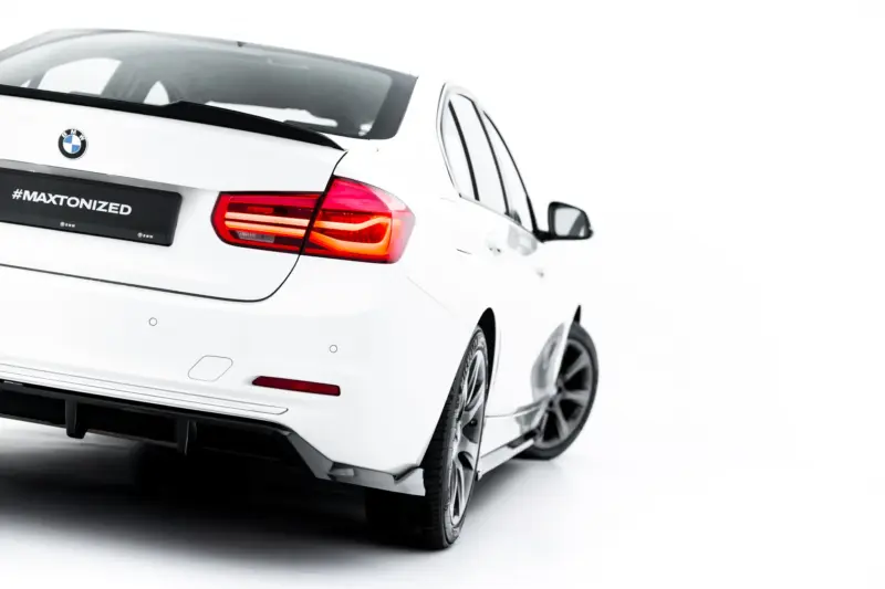 Rear 3/4 view of a white BMW showing the taillight, bumper, and a license plate reading #MAXTONIZED.