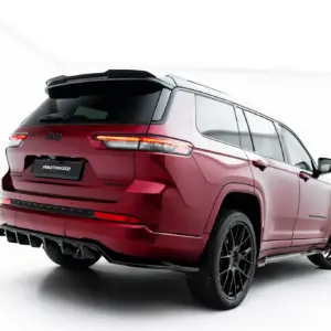 Red Jeep SUV viewed from the rear-right at a three-quarter angle, showing taillights, spoiler, and large dark wheels.