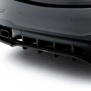 Close-up of a dark car's rear bumper with dual exhaust outlets and diffuser surface details.