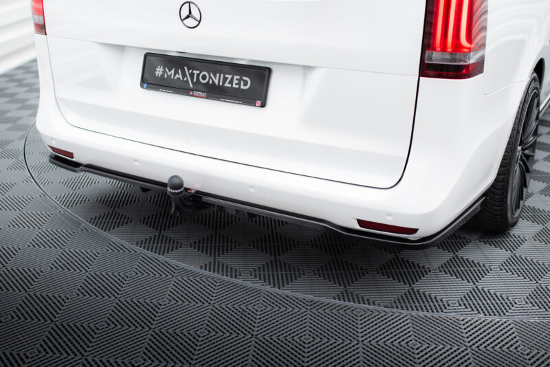 Rear view of a white Mercedes van with a black license plate reading #MAXTONIZED on a checkered showroom floor.