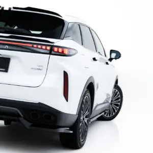 Rear three-quarter view of a white SUV with a spoiler and red LED taillights, hashtagged #MAXTONIZED on the license area, showing AWD badge and large alloy wheels.