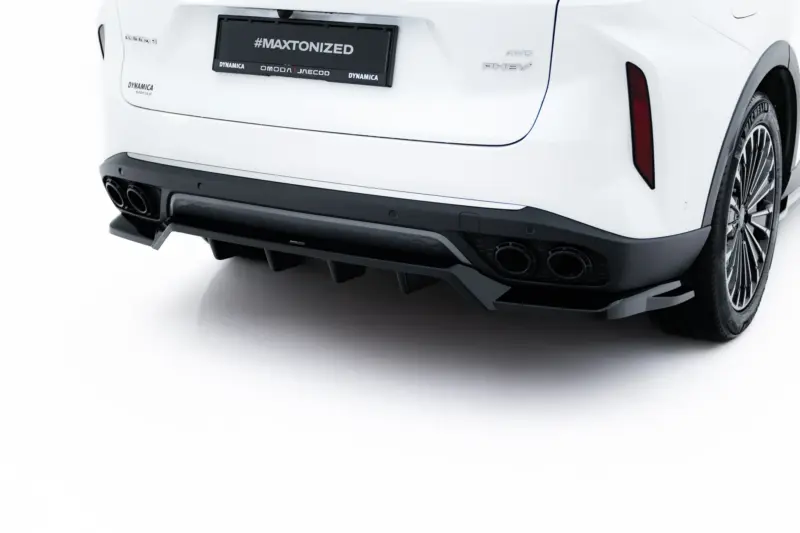Rear view of a white car highlighting the quad exhausts and sporty diffuser with a large wheel visible on the right, license plate reads #MAXTONIZED.