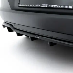 Close-up of a dark car rear bumper with a small Maxton Design badge visible along the lower trim.