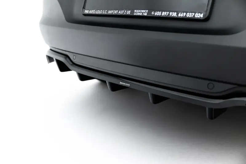 Close-up of a dark car rear bumper with a small Maxton Design badge visible along the lower trim.