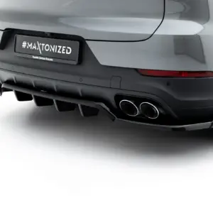 Rear view of a silver car showing a license plate with '#MAXTONIZED' and 'Porsche Centrum Rzeszów' text, plus quad exhausts and a visible tire on the right side.