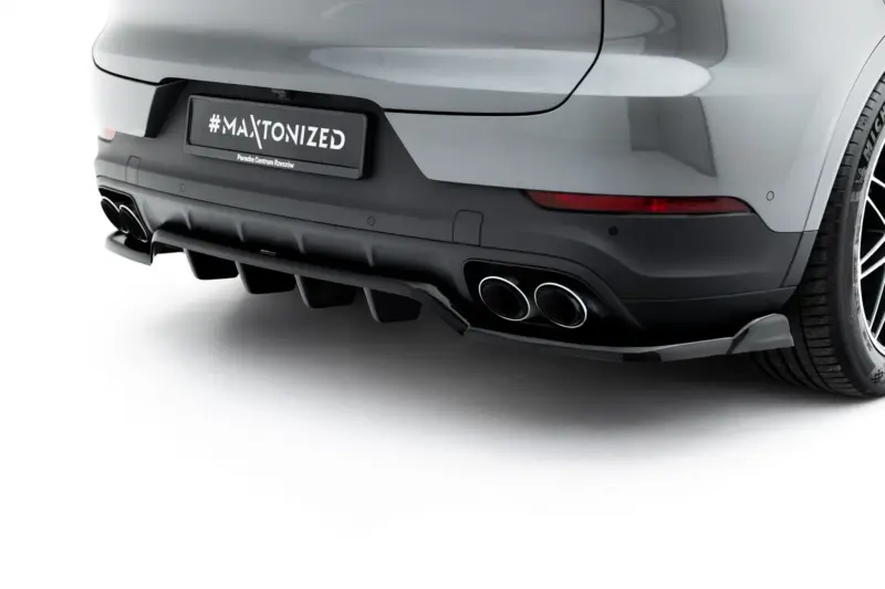 Rear view of a silver car showing a license plate with '#MAXTONIZED' and 'Porsche Centrum Rzeszów' text, plus quad exhausts and a visible tire on the right side.
