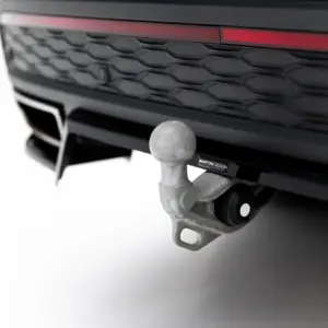 Close-up of a tow hitch ball attached to a vehicle's hitch beneath the front bumper and grille with a red accent light behind.