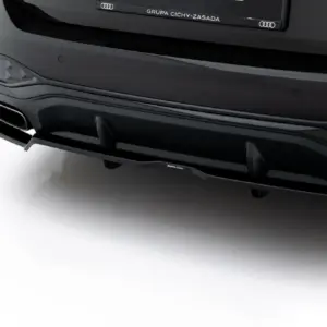 Rear of a black Audi showing quad exhaust tips, sculpted diffuser, and the quattro badge on the tail.