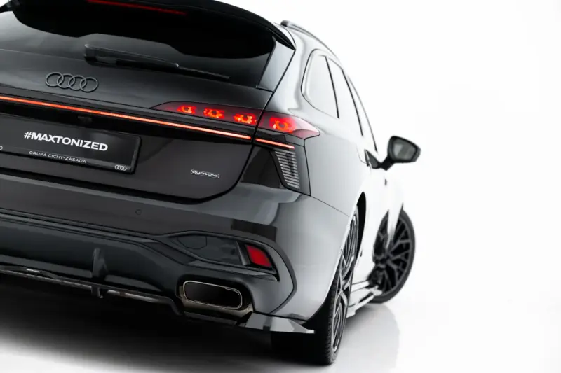 Rear view of a black Audi SUV showing red taillights, Audi rings, and a #MAXTONIZED plate with quattro badge visible on the tailgate