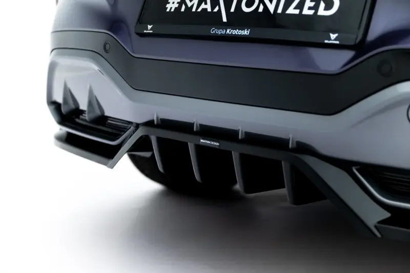 pol_po_Rear-Splitter-with-vertical-bars-V-3-Cupra-Terramar-Mk1-Version-with-towbar-23819_2webp - OPSHOLDERS Close-up of a dark gray car bumper with angular fins and a small Maxton Design badge visible underneath the bumper edge.
