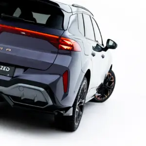 Rear three-quarter view of a dark blue Cupra SUV, showing illuminated red tail lights, the Cupra badge, and a license plate reading #MAXTONIZED