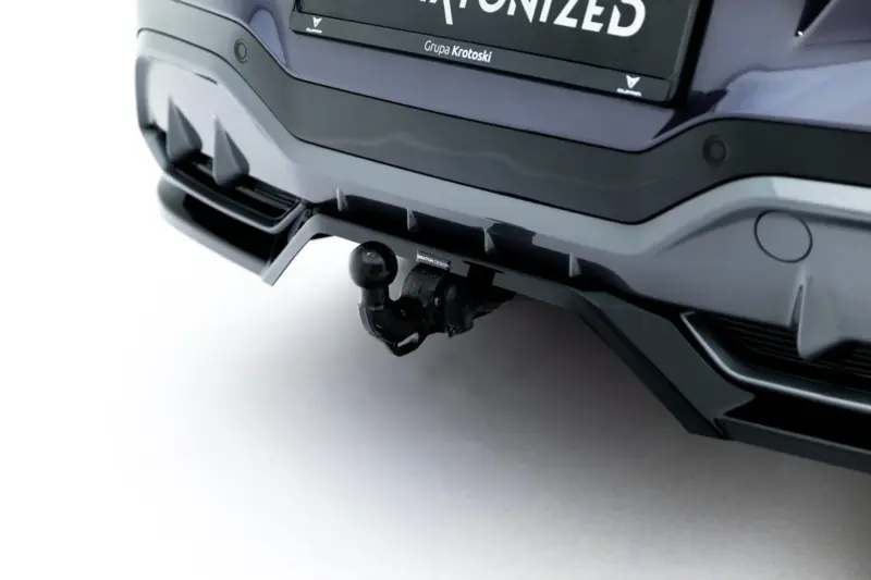Close-up of a car's rear showing a trailer hitch ball and mounting bracket beneath the bumper.