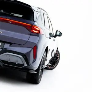 Rear three-quarter view of a dark gray CUPRA SUV showing red illuminated taillights and the CUPRA badge on the tailgate, angled to the left.