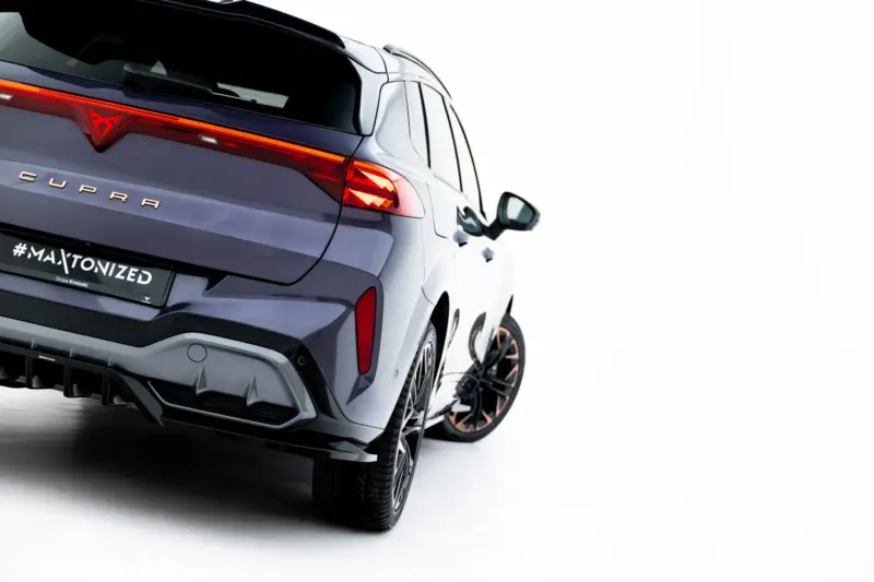 Rear three-quarter view of a dark gray CUPRA SUV showing red illuminated taillights and the CUPRA badge on the tailgate, angled to the left.