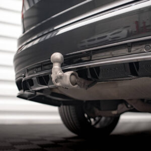 Close-up of a silver trailer hitch ball attached to a car's rear bumper, with underside components visible beneath the bumper.